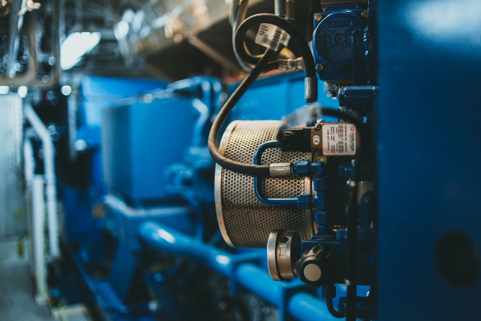 Ruang mesin genset industri dengan filter, hose, dan komponen engine